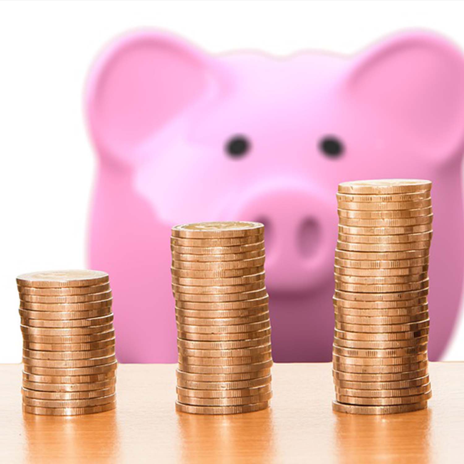Image of stacks of pennies with a large pink piggy bank in the background.