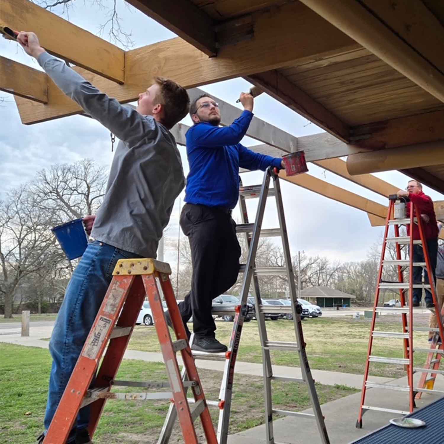 Photo of Union State Bank staff on ladders painting an outdoor structure.