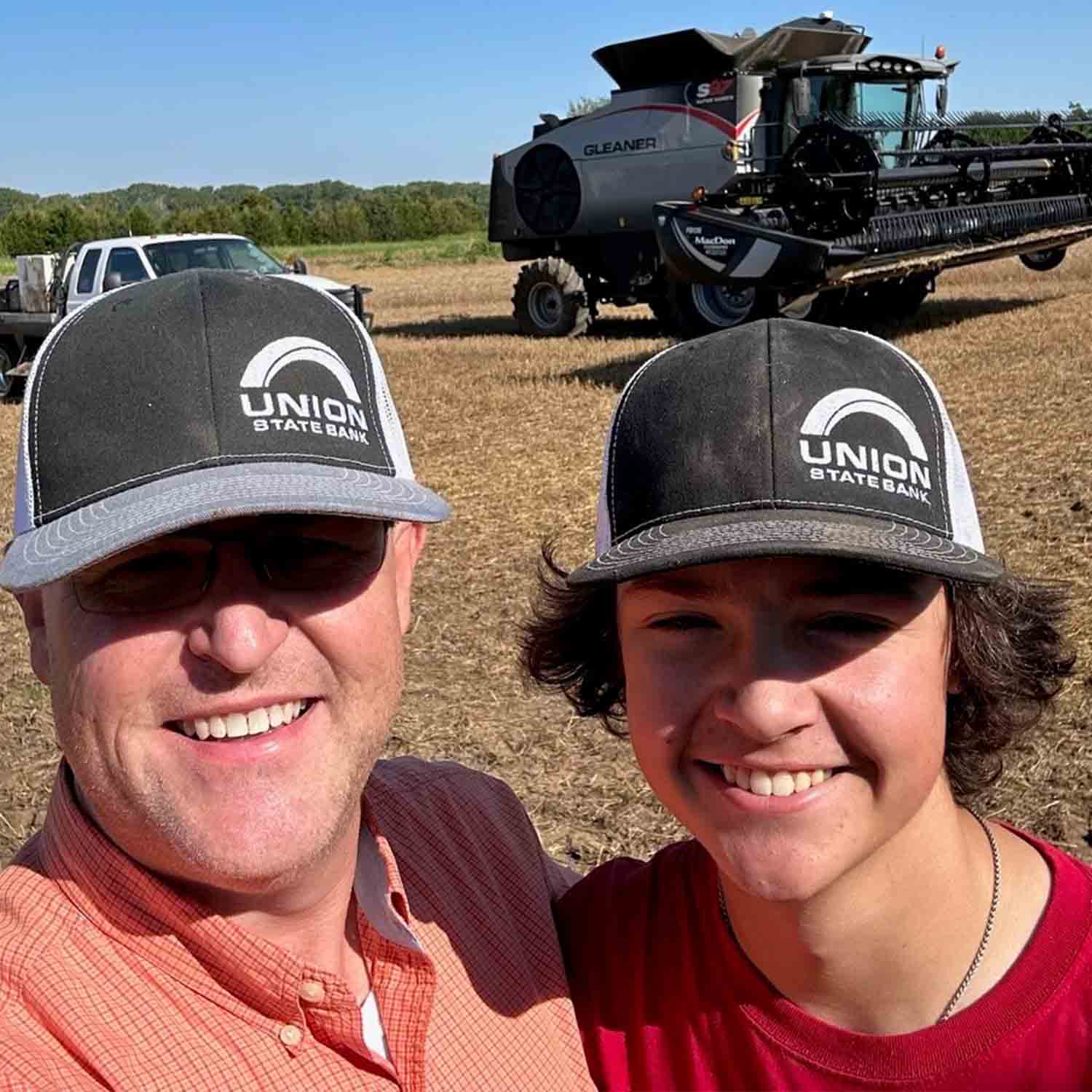 Photo of USB Market President for Arkansas City, Bradley Bryant and his son Bennett in a wheat field with equipment in the background.