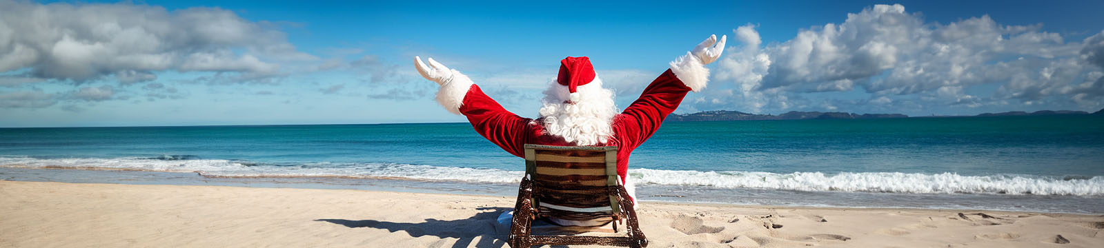 AI generated image of santa claus sitting in a beach chair relaxed while looking at the ocean.