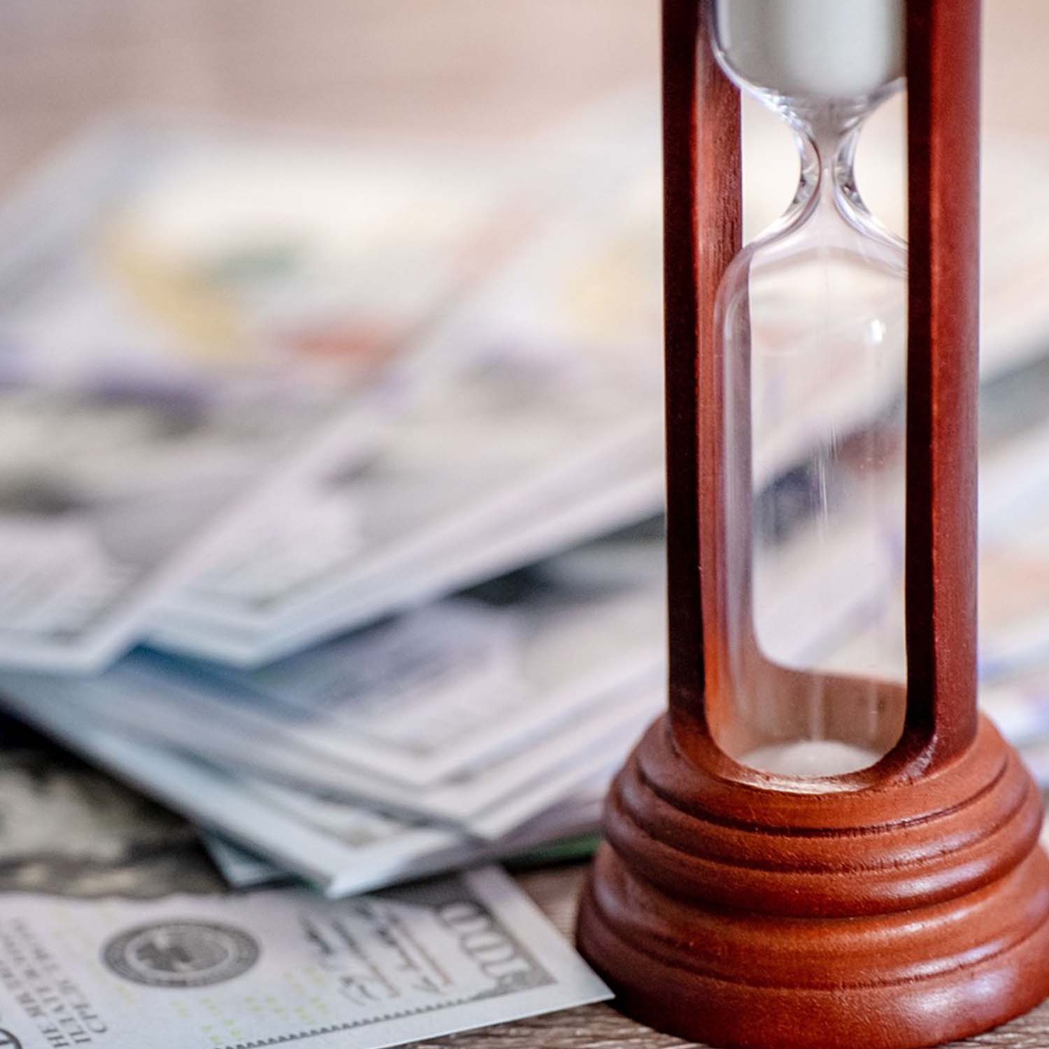 Photo of an hour glass beside a pile of money.