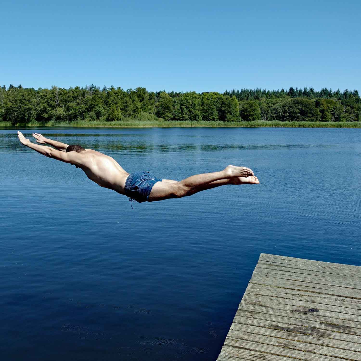 Photo of a man diving into a lake.